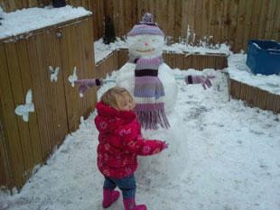 2 Year old Nia Godwin putting the finishing touches to the snowman in her garden. 
