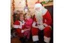 Chole Bartlett, two, from Cwmbran meets Father Christmas and his helper Linda Davies at the St Annes Hospice Santa's Grotto in Newport market