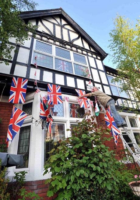 Graham Wheeler up a ladder outside his home in Newport putting the flags up for the royal wedding celebrations