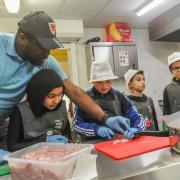 Tony Ogunsulire, Director of Steps4Change, at the Butetown Pavilion, leads a cooking class for children, teaching them life skills.