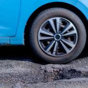 General picture of a car travelling past a pothole.
