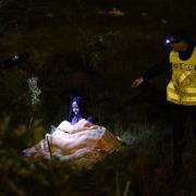 CRISIS: A migrant mother and her five-year-old child (hidden under blanket) are approached by a French police officer during a nightly sweep of the perimeter fence of the Eurotunnel site in Calais. Do we want these people washed from the streets by water