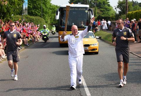 Torchbearer 027 Graeme Knowles carries the Olympic Flame on the Torch Relay leg through Ross on Wye