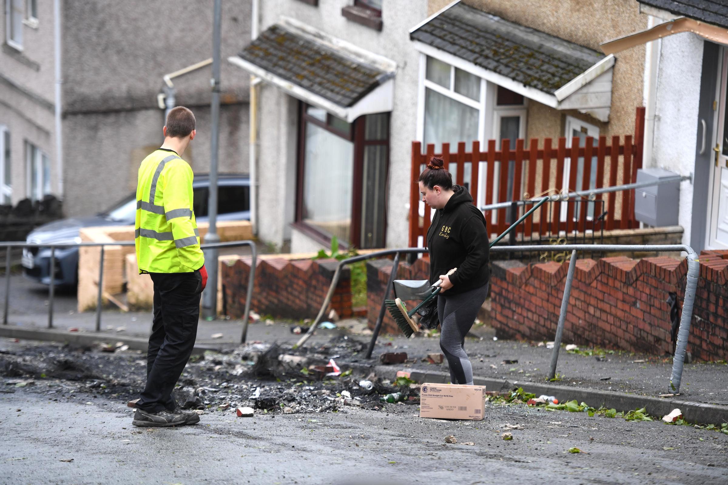 21.05.21 - Local residents and council workers clear up after cars were burnt out and windows smashed during the violence and riots in the Mayhill area of Swansea, South Wales last night.