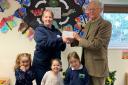 Sir Mark Hudson presenting the cheque to Kaya Ross, manager of Munchkins, with Ede, Jessica and Amelia.