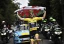 Britain's Geraint Thomas, wearing the overall leader's yellow jersey, holds the flag of Wales during the 21st and last stage of the 105th edition of the Tour de France cycling race between Houilles and Paris Champs-Elysees, Sunday, July 29, 2018.