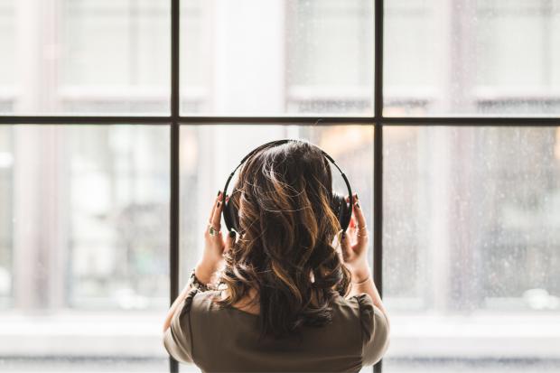 South Wales Argus: A woman listening to music on her headphones. Credit: Canva