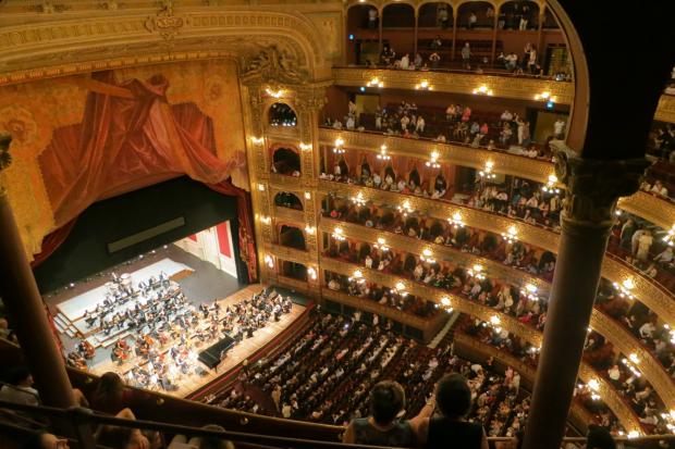 South Wales Argus: A grand theatre with people watching an orchestra. Credit: Canva