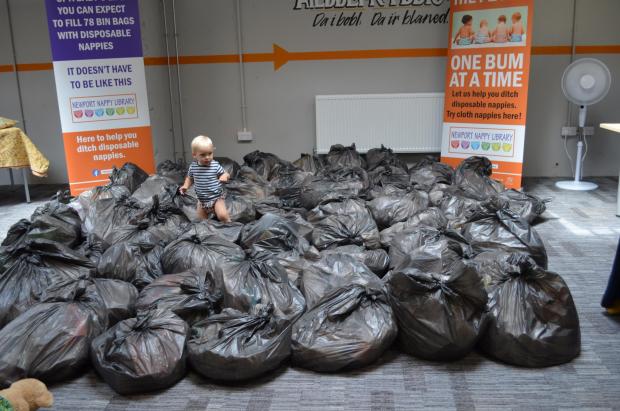 South Wales Argus: A baby sits in numerous bags of nappy waste: Photo Credit: Wastesavers and Newport Nappy Library