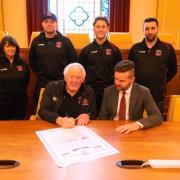 Pictured signing the scroll are Graham Price and Cllr Anthony Hunt. Standing back row left to right are Gill Calder, Pontypool RFC's Hospitality Manager, current Pontypool RFC players Callum Davies and Matt Bancroft and club Secretary Jamie Hallam