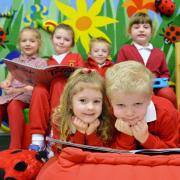 Tommy Burke, (front right) a Year 1 pupil helping nursery pupil Alys-Marie Hawkins-Price (left) with her reading in the nursery reading group