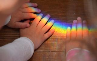 Children with hands on a rainbow